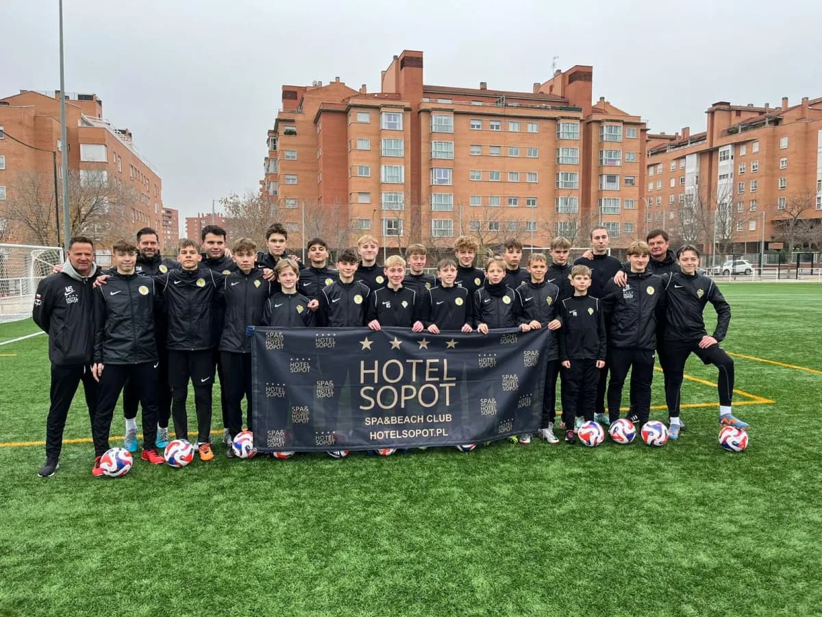 Grupo de jugadores y entrenadores posando con balones en un campo de entrenamiento en Madrid