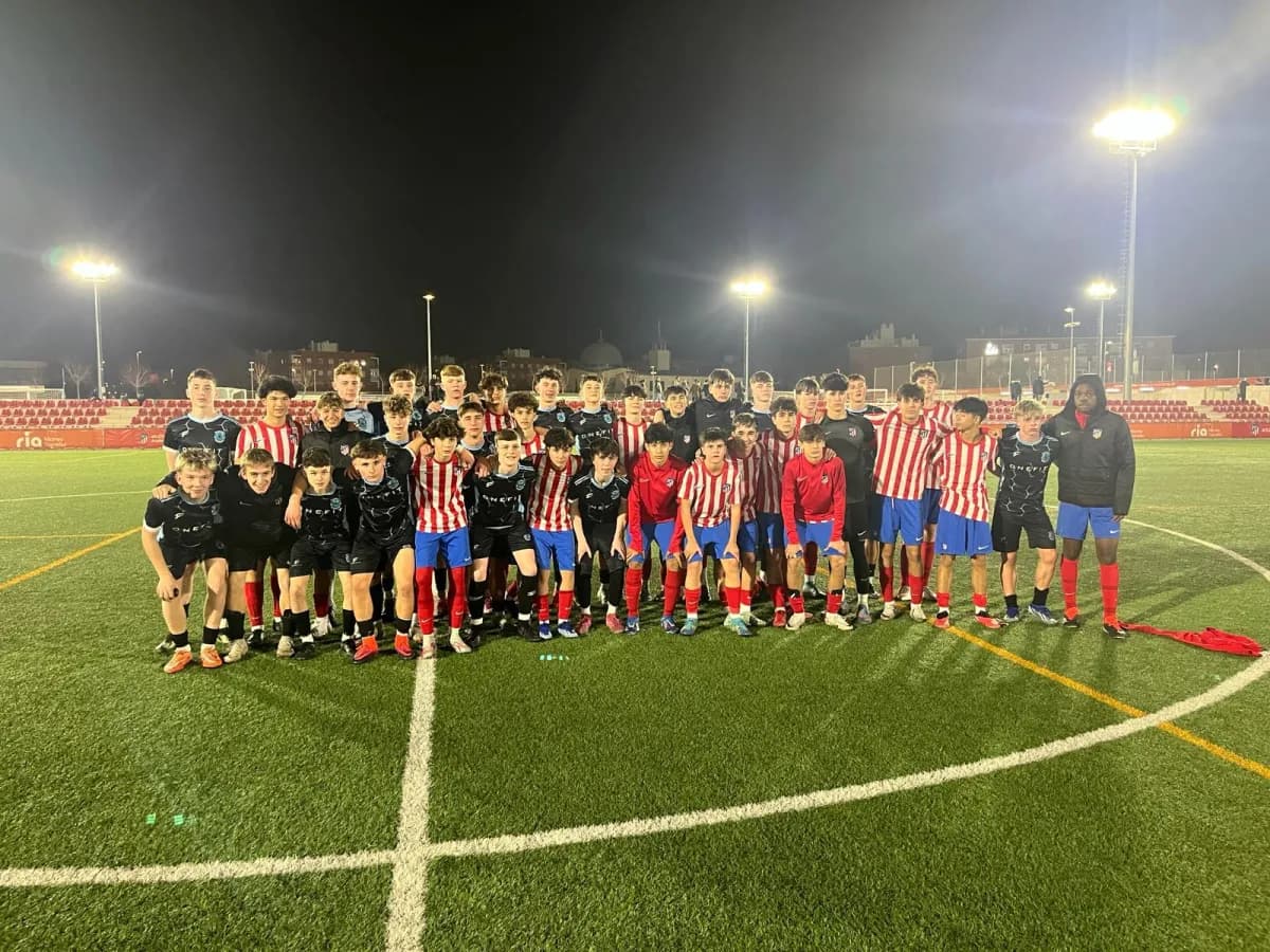 Dos equipos juveniles posando juntos en el campo tras un partido nocturno