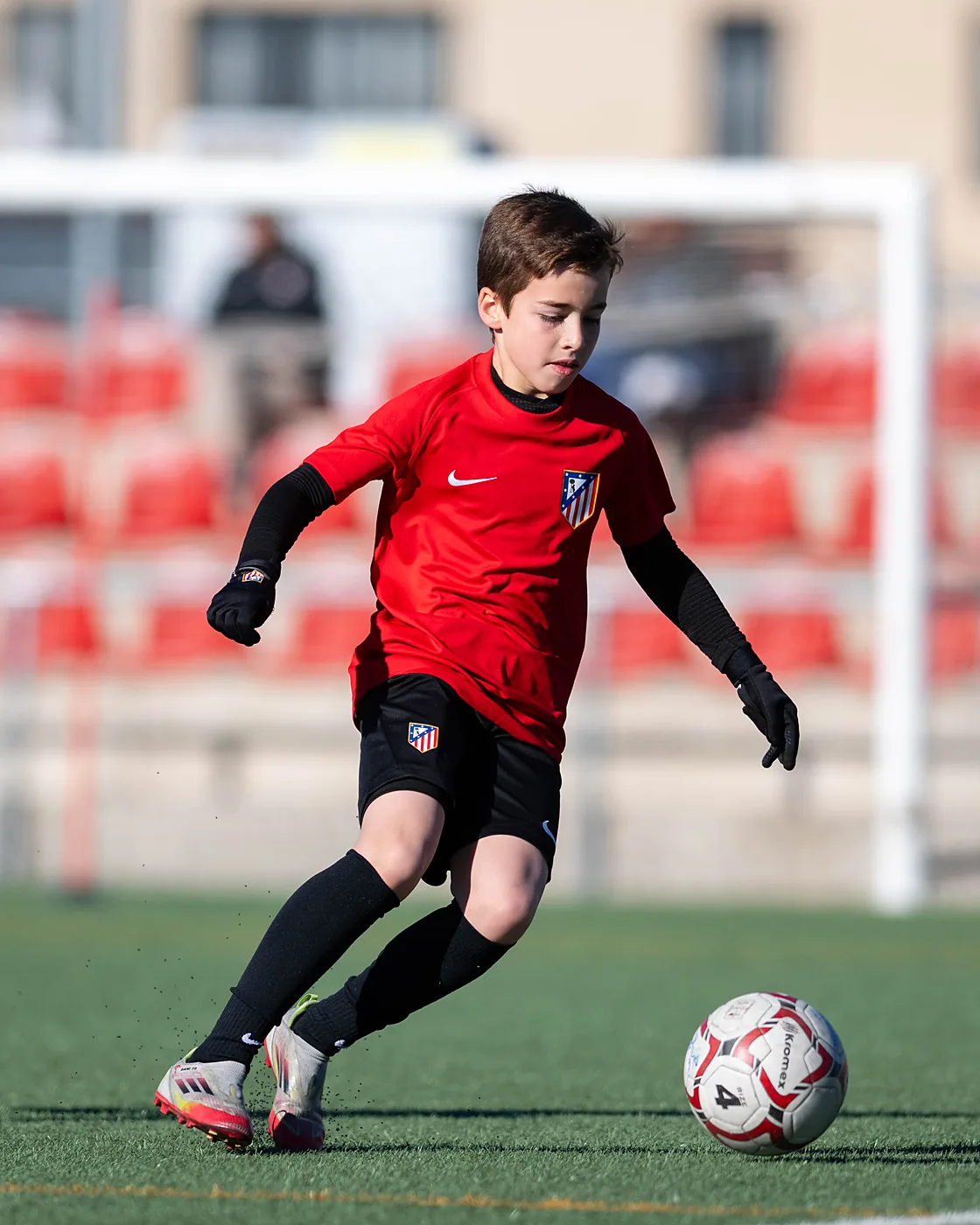 Jugador conduce el balón con la equipación de la Academia Atlético de Madrid